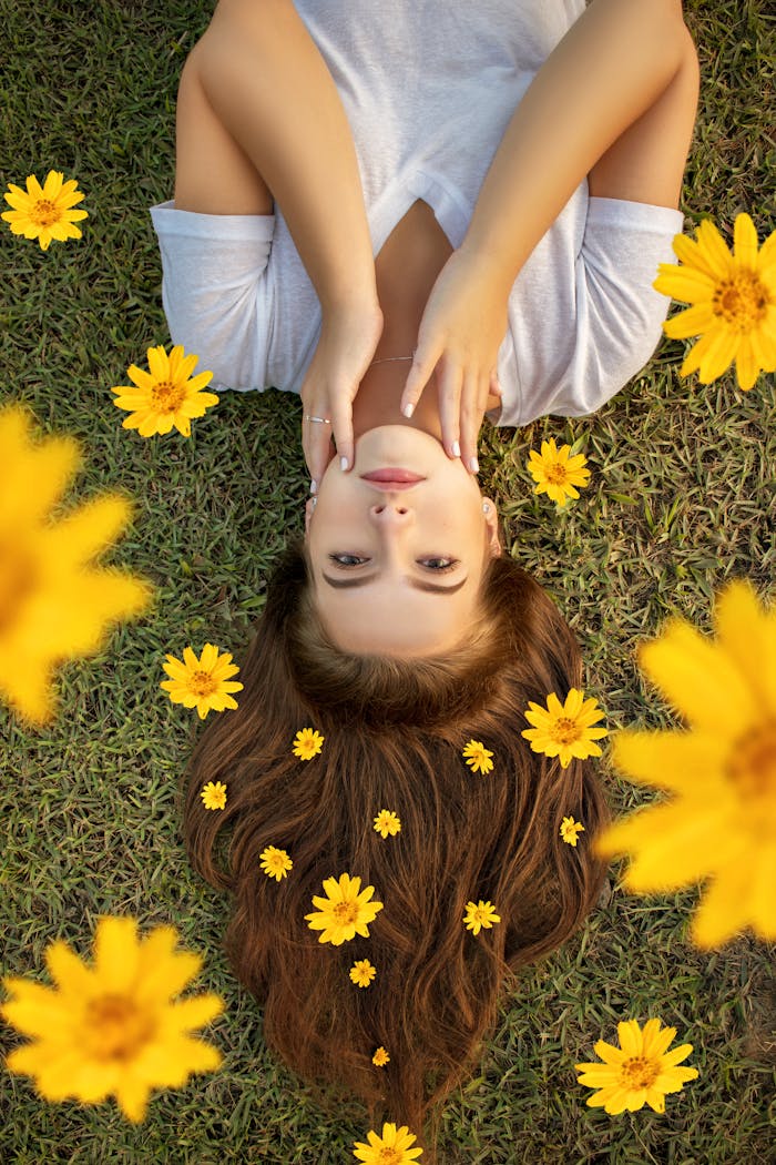 Home Upside down portrait of a woman lying on grass with yellow flowers in her hair.